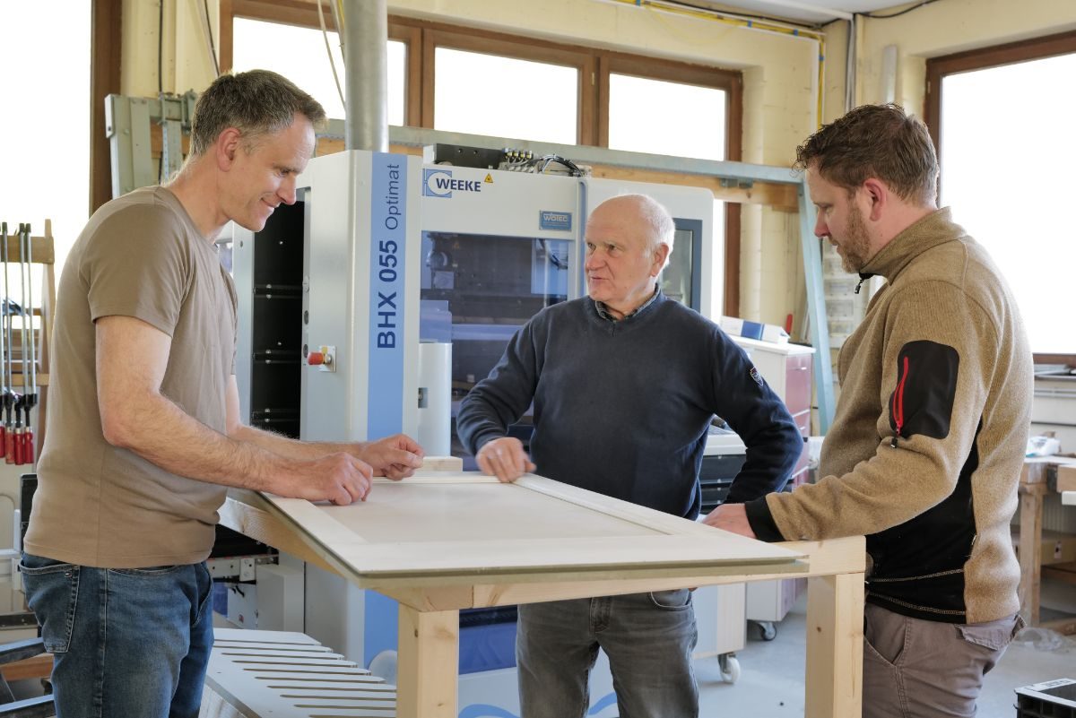 Das Team der Schreinerei Zintl in der Werkstatt an einer Füllung der Wandvertäfelung
